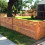 Horizontal natural wood fence around a front yard with grass and sidewalk