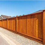 Tall vertical wood privacy fence along a residential driveway