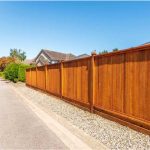 Tall vertical wood privacy fence along a residential driveway