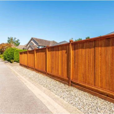 Tall vertical wood privacy fence along a residential driveway