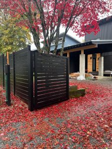 Black aluminum privacy fence with horizontal slats and matching driveway gate in Shoreline, WA