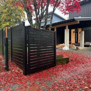 Black aluminum privacy fence with horizontal slats and matching driveway gate in Shoreline, WA