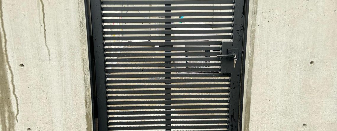 Black horizontal slat metal gate installed between concrete walls in Bellevue, WA