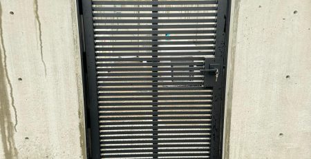 Black horizontal slat metal gate installed between concrete walls in Bellevue, WA